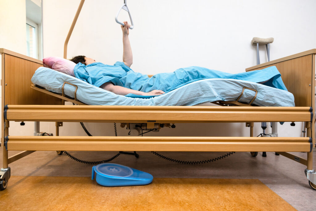 side view of curved homecare electric hospital bed with patient holding handle at home