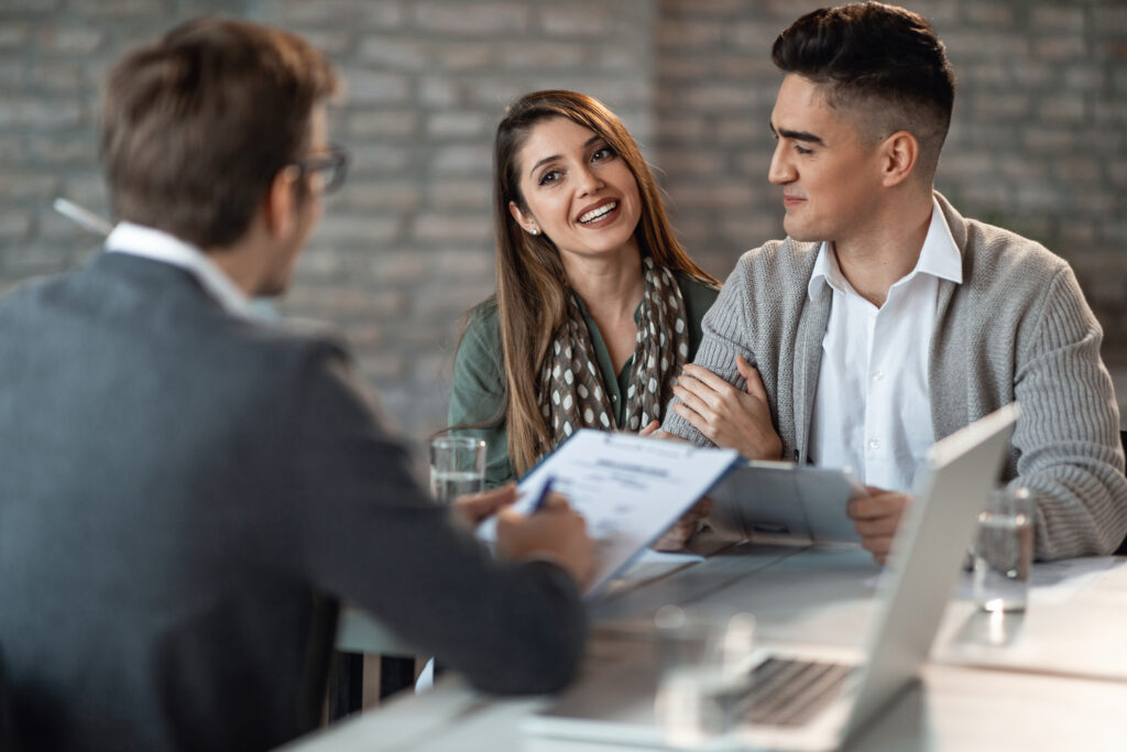 Young happy couple having a meeting with insurance agent in the office. Focus is on woman.